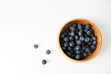 Blueberry in a wooden bowl placed on a white table