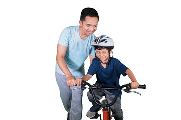 Fototapeta na wymiar Happy child learns to ride a bike with his father