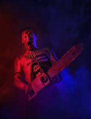 Terrible man with chainsaw screaming. Halloween scene