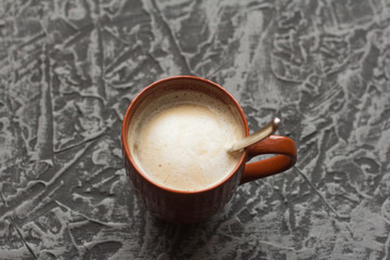 hot cappuccino coffee in a brown mug on a gray background