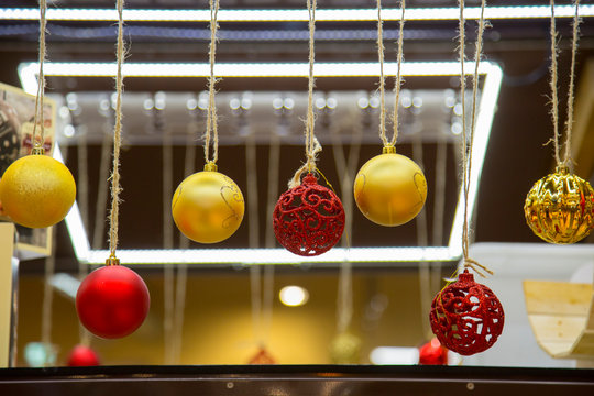 horizontal image with detail of seven christmas balls hanging with string in a shop