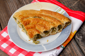 Pastry with cheese and spinach and red dish towel on an retro style wooden table