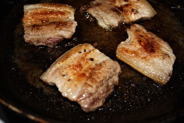 Fried crispy pork belly in a frying pan, view from above