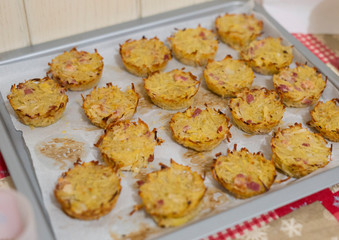 horizontal image with detail of baked pies with potatoes and speck photographed in a pan, prepared for a party