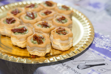 horizontal image with vol-au-vent detail with pesto sauce and dried tomatoes, served on a tray and prepared for a party