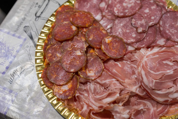 horizontal image with detail of typical Italian products, salami ham, bacon, served on a tray