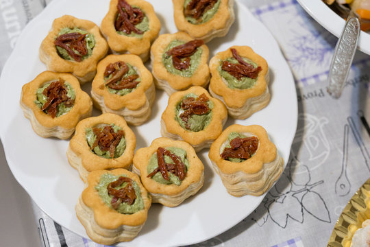horizontal image with vol-au-vent detail with pesto sauce and dried tomatoes, served on a tray and prepared for a party