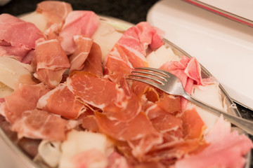 horizontal image with detail of typical Italian products, salami ham, bacon, served on a tray