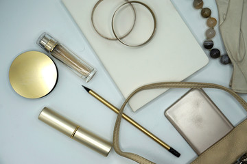 Flat lay composition of beauty products and handbag for women. Pastel and gold colors on white background. Top view.     