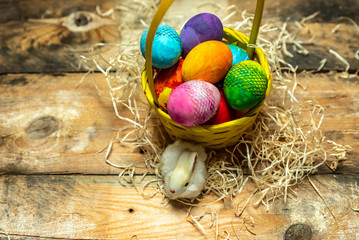 beautiful, bright, colorful hand-painted Easter eggs in a yellow basket on a natural, wooden background