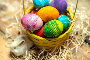 beautiful, bright, colorful hand-painted Easter eggs in a yellow basket on a natural, wooden background