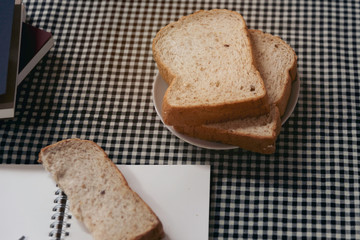 Color book and pen put near slid bread,all put on black and white table cloth.