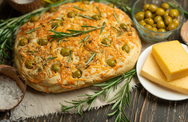 Italian focaccia bread with rosemary and cheese on a rustic background