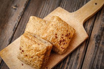 Healthy homemade pastry with integral flour and seeds on kitchen cutting board. Wooden table and rustic vintage background.