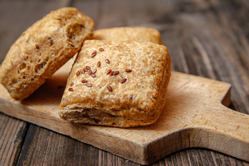 Healthy homemade pastry with integral flour and seeds on kitchen cutting board. Wooden table and rustic vintage background.