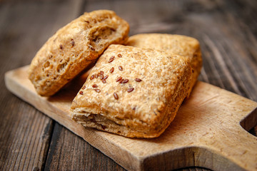 Healthy homemade pastry with integral flour and seeds on kitchen cutting board. Wooden table and rustic vintage background.