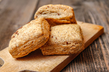 Healthy homemade pastry with integral flour and seeds on kitchen cutting board. Wooden table and rustic vintage background.