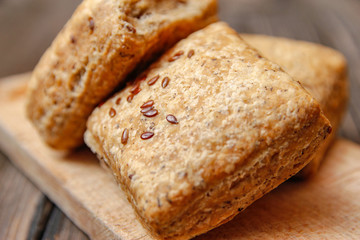 Healthy homemade pastry with integral flour and seeds on kitchen cutting board. Wooden table and rustic vintage background.