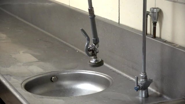 Sink sprayer swinging over a dingy commercial stainless work area