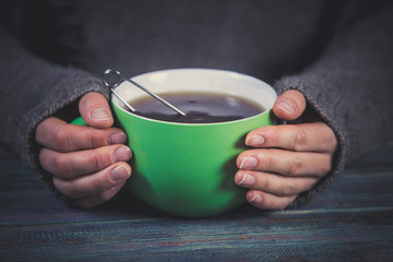 Woman holds a cup of hot tea. Cozy morning at home.