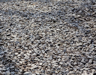 Texture of gray gravel. Grey stony floor. A wall of gray gravel. Stones small and medium-sized. Sharp edges of the stones. Sand and stones on the floor. The land is covered with stones