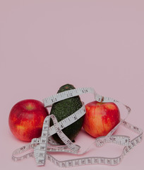 Red apples with a yardstick with avocado on pink background. Diet food concept. Diet food ingredient