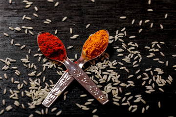 spices in spoons on black background