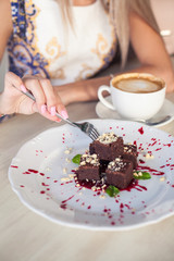 Young beautiful blonde with blue eyes is sitting in a cafe. A young woman holds a cappuccino mug in her hands. Portrait of a young happy woman. Fashion. Makeup. Summer.
