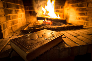 Obraz premium Old book beside fireplace
