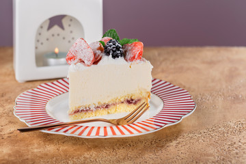 piece of cottage cheese cake with strawberries, blackberries and mint on a beautiful festive plate.
