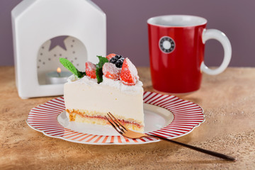 piece of cottage cheese cake with strawberries, blackberries and mint on a beautiful festive plate.
