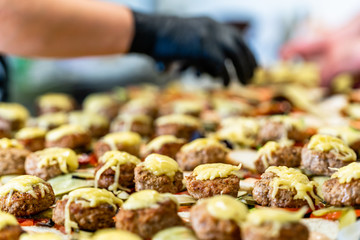 Female and Male Chef Putting Ingredients of Burgers on a Sliced Bread Spread on a Table in Black Gloves