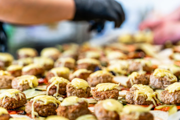 Female and Male Chef Putting Ingredients of Burgers on a Sliced Bread Spread on a Table in Black Gloves