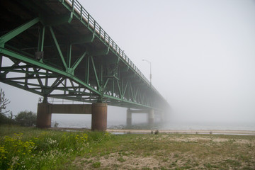 Fog Rolls In Under The Mackinaw Bridge. The bridge spans the Straits Of Mackinaw between Michigan's Upper Peninsula and Lower Peninsula.