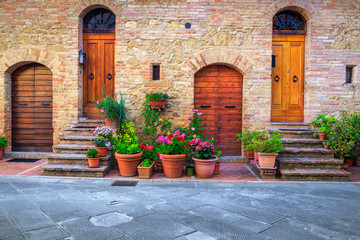 Fototapeta na wymiar Floral entrance and wooden door in Tuscany, Pienza, Italy