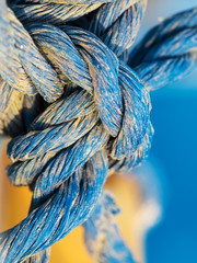 Knot made of blue twisted rope in the grains of sand in detail, marine concept, macro