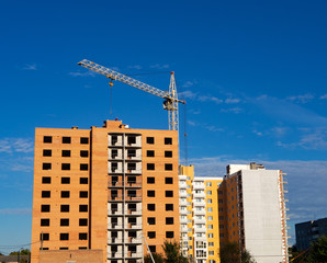 Fototapeta na wymiar Construction site of brick multistory building with crane under blue sky, new condominium on the background. Affordable housing
