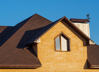 Multilevel roof of modern brick house with window and rain gutters
