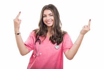Portrait of beautiful young doctor wearing scrubs showing double middle finger