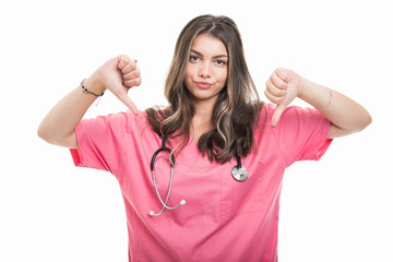 Portrait of beautiful young doctor wearing scrubs showing double dislike