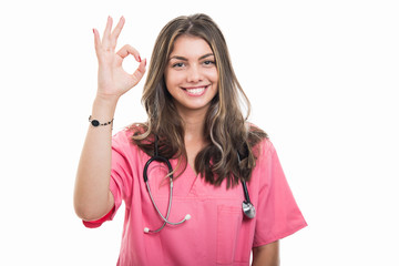 Portrait of beautiful young doctor wearing scrubs showing ok gesture