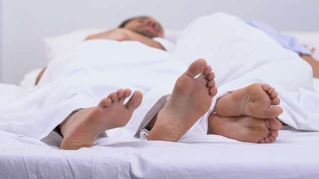 Man touching feet of angry woman, quarrel in bed in morning, problem in marriage