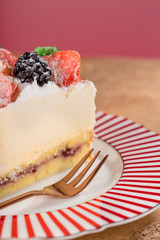 Close-up piece of cottage cheese cake with strawberries, blackberries and mint on a beautiful festive plate. Vertical.