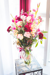burgundy pink and green wedding florals on a glass table