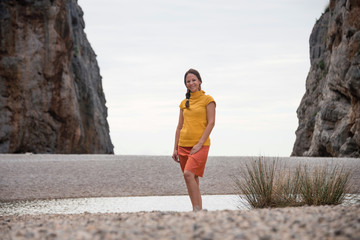 Young woman posing on the small pebble beach in Torrent de Pareis - deepest canyon of Mallorca island, Spain