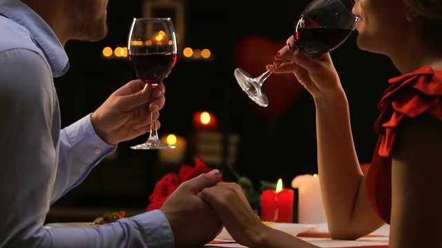 Couple in love chatting drinking red wine, cozy Saint Valentines Day celebration