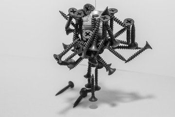 Abstract figurine of black self-tapping screws hanging on the magnet