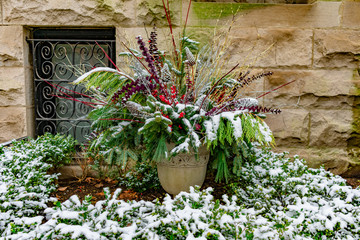 Holiday Planter with Pine Branches outside of a Home in a Garden Covered with Snow during Winter