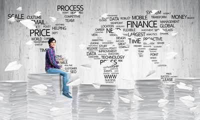 Attractive man sitting on pile of paper documents.