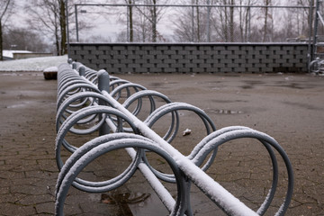 bike rack in steel in the winter with snow and a fence in the background
